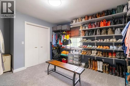 Expansive walk-in closet featuring extensive built-in shelving, carpet flooring, bi-fold closet doors, a rectangular window, and recessed lighting - 111 Decou Road, Simcoe, ON - Indoor