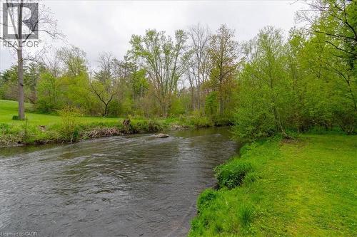 Waterfront property featuring a flowing river, lush green grass, mature trees, and natural landscaping - 111 Decou Road, Simcoe, ON - Outdoor With Body Of Water