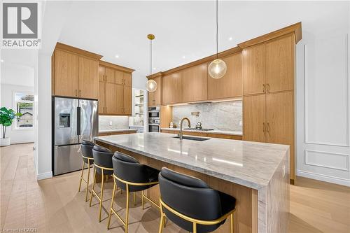 Gourmet kitchen featuring custom wood cabinetry, stainless steel appliances, a large center island with stone countertop, and pendant lighting - 67 Cielo Court, Hamilton, ON - Indoor Photo Showing Kitchen