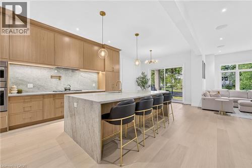Light wood-finish flooring, full-height cabinetry, kitchen island with seating, stainless steel appliances, and a sliding glass door - 67 Cielo Court, Hamilton, ON - Indoor Photo Showing Kitchen With Upgraded Kitchen