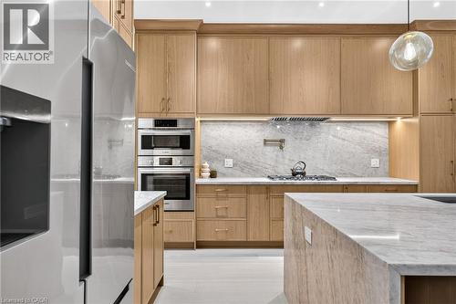 Light wood cabinetry with integrated stainless steel appliances, a pot filler, under-cabinet lighting, and stone countertops - 67 Cielo Court, Hamilton, ON - Indoor Photo Showing Kitchen With Upgraded Kitchen