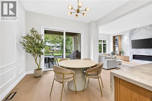 Light wood-finish flooring, accent wall paneling, a contemporary chandelier, and a sliding glass door providing access to an outdoor area - 67 Cielo Court, Hamilton, ON - Indoor Photo Showing Other Room With Fireplace