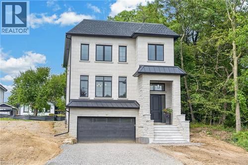 Stone facade with dark-framed windows, a prominent covered entrance, and a dark garage door - 67 Cielo Court, Hamilton, ON - Outdoor With Facade