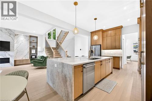 Kitchen island with integrated sink, stainless steel dishwasher, and quartz countertop - 67 Cielo Court, Hamilton, ON - Indoor Photo Showing Kitchen With Fireplace