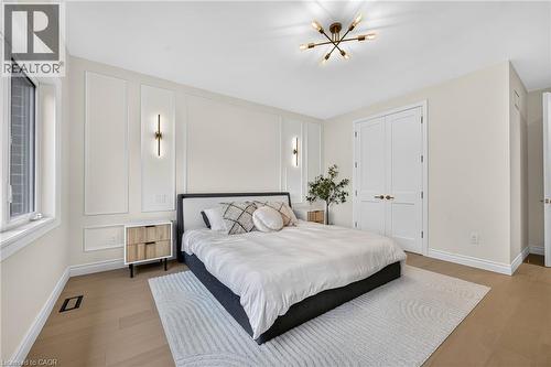 Neutral wall tones with decorative wall molding, wood-finish flooring, and a modern ceiling light fixture - 67 Cielo Court, Hamilton, ON - Indoor Photo Showing Bedroom