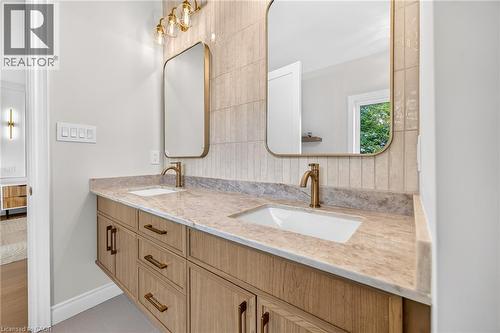 Floating dual vanity with wood-finish cabinetry, integrated sinks, and brass-tone fixtures - 67 Cielo Court, Hamilton, ON - Indoor Photo Showing Bathroom