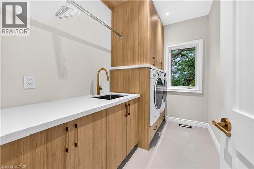 Built-in wood-finish cabinetry, white countertop, undermount sink with a gold-finish faucet, and a window with exterior views - 67 Cielo Court, Hamilton, ON - Indoor