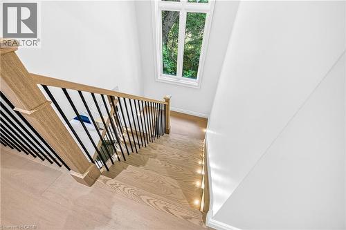 Hardwood stair treads with integrated lighting, wood newel posts, and a black wrought iron spindle railing - 67 Cielo Court, Hamilton, ON - Indoor Photo Showing Other Room