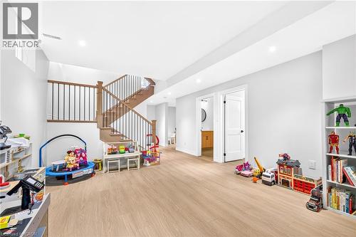 Spacious room with wood-finish flooring, recessed lighting, and a two-tone staircase with wood treads and black metal balusters - 67 Cielo Court, Hamilton, ON - Indoor Photo Showing Other Room