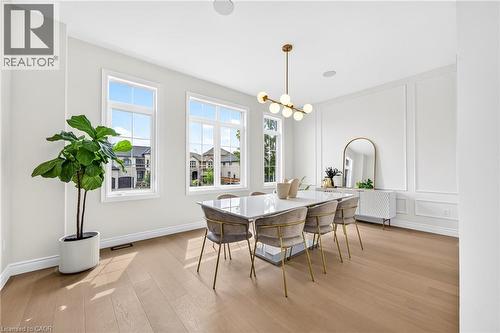 Light wood-finish flooring, multiple pane windows, modern chandelier, recessed lighting, and decorative wall molding - 67 Cielo Court, Hamilton, ON - Indoor Photo Showing Dining Room