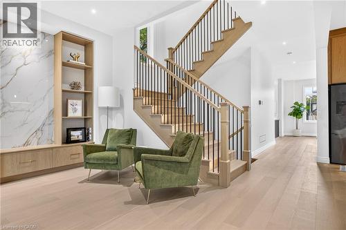 Hardwood flooring, custom built-in cabinetry, large format wall paneling, open-tread staircase with black iron spindles, recessed lighting - 67 Cielo Court, Hamilton, ON - Indoor Photo Showing Other Room