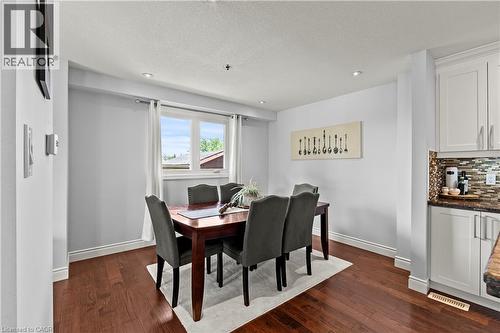 Wood-finish flooring, recessed ceiling lighting, a double window with white trim, white cabinetry, and a textured tile backsplash - 87 Monte Drive, Hamilton, ON - Indoor Photo Showing Dining Room