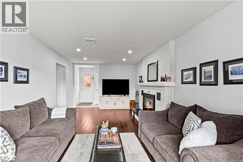 White brick fireplace with mantel, recessed lighting, wood-finish flooring, and white walls - 87 Monte Drive, Hamilton, ON - Indoor Photo Showing Living Room