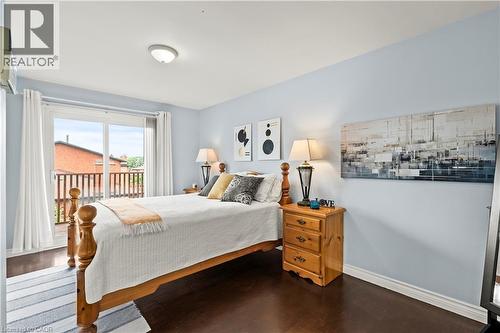 Sliding glass door leading to a balcony with wood railing, dark wood-finish flooring, and light blue wall color - 87 Monte Drive, Hamilton, ON - Indoor Photo Showing Bedroom