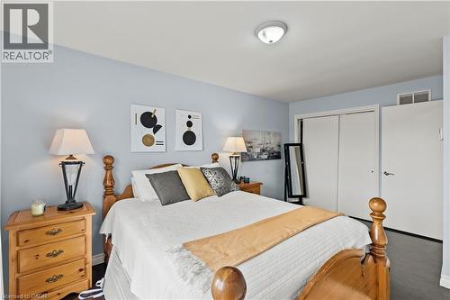Light blue painted walls, wood-finish flooring, flush mount ceiling light, and built-in closet with sliding doors - 87 Monte Drive, Hamilton, ON - Indoor Photo Showing Bedroom