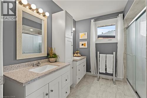 Bathroom featuring a single vanity with a rectangular sink, speckled countertop, white cabinetry, and a glass-enclosed shower - 87 Monte Drive, Hamilton, ON - Indoor Photo Showing Bathroom