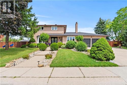 Brick exterior with a two-car garage, mature landscaping, and a concrete pathway leading to the front entry - 87 Monte Drive, Hamilton, ON - Outdoor