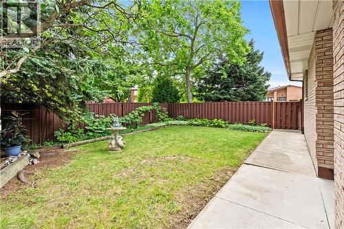 Private fenced yard with mature trees, established perennial plantings, and a concrete pathway - 87 Monte Drive, Hamilton, ON - Outdoor