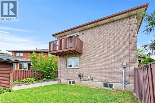 Brick exterior with an upper-level wood balcony, white-framed windows, and a manicured lawn - 87 Monte Drive, Hamilton, ON - Outdoor With Exterior