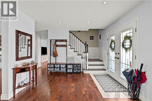 Hardwood-finish flooring, white double entry doors with leaded glass, recessed lighting, white wainscoting, and a staircase with white risers and dark wood treads - 87 Monte Drive, Hamilton, ON - Indoor Photo Showing Other Room