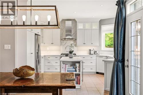 White cabinetry, stainless steel appliances, tiled flooring, wood-finish dining table, and a contemporary chandelier - 536 Cusick Circle, Milton, ON - Indoor Photo Showing Kitchen With Upgraded Kitchen