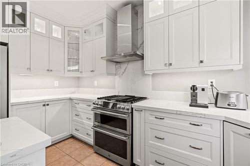 Sleek chef's kitchen featuring white shaker cabinetry, stainless steel dual-oven range with gas cooktop, professional-grade range hood, quartz countertops, subway tile backsplash, and brushed nickel h - 536 Cusick Circle, Milton, ON - Indoor Photo Showing Kitchen With Upgraded Kitchen