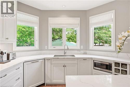 Bright, light-filled kitchen featuring white cabinetry with shaker-style doors, quartz countertops, and a centered undermount sink with polished nickel faucet - 536 Cusick Circle, Milton, ON - Indoor Photo Showing Kitchen
