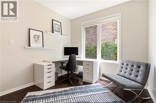 Dedicated home office featuring a corner desk configuration with built-in storage cabinetry, a black task chair, and abundant natural light from French doors opening to outdoor space - 536 Cusick Circle, Milton, ON - Indoor
