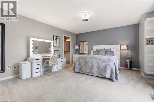 Spacious primary bedroom suite featuring neutral carpeting, dual vanity with illuminated mirror and storage drawers, recessed ceiling lighting, and an ensuite bathroom - 536 Cusick Circle, Milton, ON - Indoor Photo Showing Bedroom
