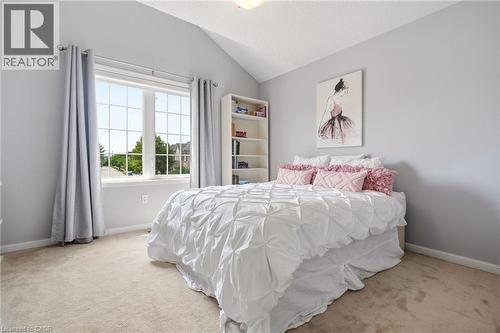 Bright secondary bedroom featuring vaulted ceilings, large multi-pane windows with grommet curtain rods, neutral carpeting, and soft gray wall paint - 536 Cusick Circle, Milton, ON - Indoor Photo Showing Bedroom