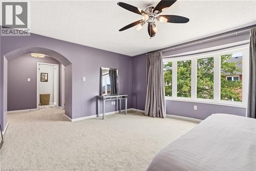 Spacious primary bedroom suite with soft purple walls, ceiling fan with brushed nickel finish, and abundant natural light from multi-pane windows - 536 Cusick Circle, Milton, ON - Indoor Photo Showing Bedroom