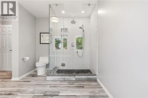Spa-inspired primary bathroom featuring a frameless glass walk-in shower enclosure with subway tile surround, dual showerheads, a separate toilet compartment, wood-finish plank flooring, and recessed - 536 Cusick Circle, Milton, ON - Indoor