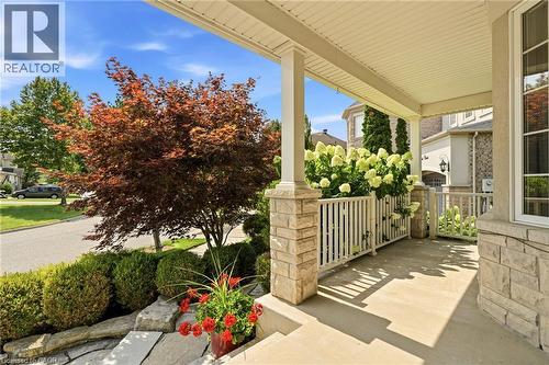 Welcoming front porch with stone columns and white railings, anchored by mature landscaping including a Japanese maple with vibrant fall foliage, manicured hedges, and seasonal plantings in decorative - 536 Cusick Circle, Milton, ON - Outdoor With Deck Patio Veranda With Exterior