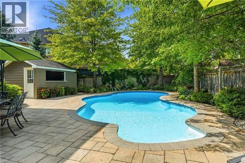 Sparkling resort-style swimming pool with curved design and shallow lounging areas, surrounded by expansive paver patio - 536 Cusick Circle, Milton, ON - Outdoor With In Ground Pool With Deck Patio Veranda With Backyard