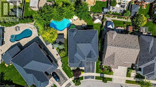 Aerial view showcasing a residence with a dark asphalt roof, manicured lawn, mature landscaping, and a resort-style swimming pool with curved design - 536 Cusick Circle, Milton, ON - Outdoor With In Ground Pool