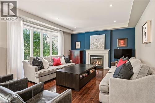 Hardwood flooring, recessed lighting, bay window, white mantle fireplace, and a tray ceiling - 536 Cusick Circle, Milton, ON - Indoor Photo Showing Living Room With Fireplace