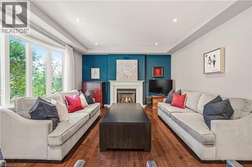 Elegant living room showcasing hardwood flooring, dual cream-upholstered sofas, and a striking teal accent wall featuring a gas fireplace with white surround - 536 Cusick Circle, Milton, ON - Indoor Photo Showing Living Room With Fireplace