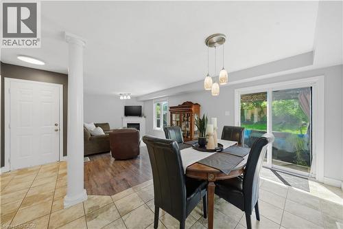 Open-concept main living area featuring tile flooring, wood-finish flooring, a white paneled door, a decorative column, and a sliding glass door to the exterior - 784 Butternut Avenue, Waterloo, ON - Indoor Photo Showing Dining Room