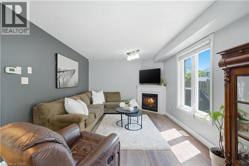 Living area featuring wood-finish flooring, a corner fireplace with a white mantel, and a large window with white trim - 784 Butternut Avenue, Waterloo, ON - Indoor Photo Showing Living Room With Fireplace
