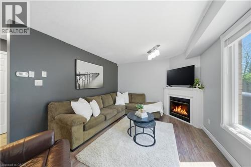 Living area featuring wood-finish flooring, a white trim window, and a corner fireplace with a white mantel - 784 Butternut Avenue, Waterloo, ON - Indoor Photo Showing Living Room With Fireplace