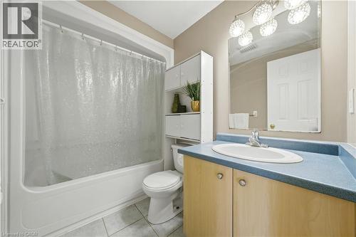 Bathroom featuring a white bathtub and shower combination, a white toilet, a light wood-finish vanity with a blue countertop and integrated sink, a large wall mirror, and a multi-bulb vanity light fix - 784 Butternut Avenue, Waterloo, ON - Indoor Photo Showing Bathroom