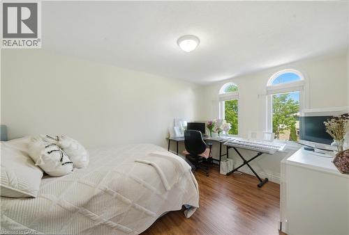 Bedroom featuring wood-finish flooring, light neutral wall paint, and two arched windows - 784 Butternut Avenue, Waterloo, ON - Indoor Photo Showing Bedroom