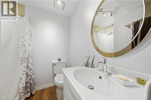 Bathroom with wood-finish flooring, a white vanity with integrated sink, and a circular mirror with a gold-toned frame - 784 Butternut Avenue, Waterloo, ON - Indoor Photo Showing Bathroom