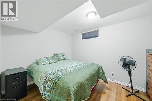 Recessed ceiling light fixture illuminating a room with wood-finish flooring, a white wall, and a horizontal window with a dark blind - 784 Butternut Avenue, Waterloo, ON - Indoor Photo Showing Bedroom