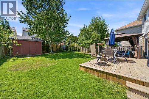 Expansive backyard featuring a wood deck with steps, a wooden privacy fence, mature trees, and a storage shed - 784 Butternut Avenue, Waterloo, ON - Outdoor