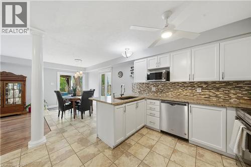 Bright kitchen featuring white shaker cabinetry, granite countertops, stainless steel appliances, and a mosaic tile backsplash - 784 Butternut Avenue, Waterloo, ON - Indoor Photo Showing Kitchen With Double Sink With Upgraded Kitchen