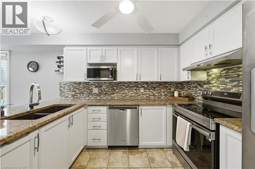 Kitchen featuring white cabinetry, granite countertops, stainless steel appliances, a mosaic tile backsplash, and tile flooring - 784 Butternut Avenue, Waterloo, ON - Indoor Photo Showing Kitchen With Double Sink With Upgraded Kitchen