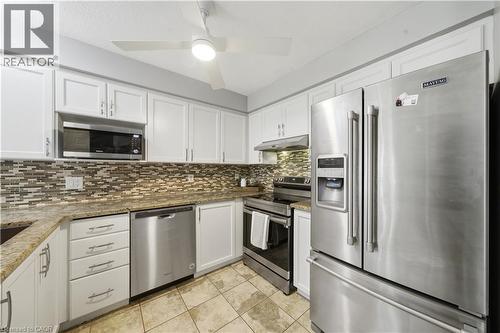 Kitchen featuring white shaker-style cabinetry, stainless steel appliances, a mosaic tile backsplash, light-toned countertops, and square tile flooring - 784 Butternut Avenue, Waterloo, ON - Indoor Photo Showing Kitchen With Upgraded Kitchen