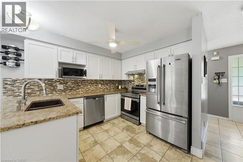 Kitchen featuring white cabinetry, stainless steel appliances, a mosaic tile backsplash, and light-toned tile flooring - 784 Butternut Avenue, Waterloo, ON - Indoor Photo Showing Kitchen With Double Sink With Upgraded Kitchen