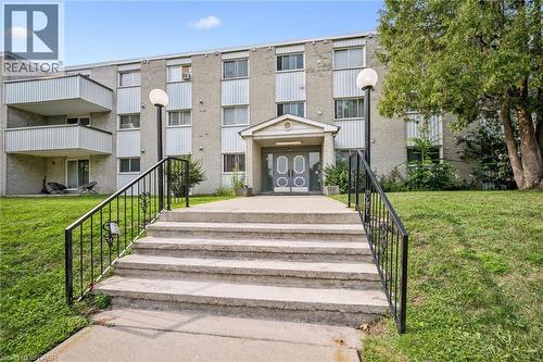 Concrete exterior with multiple balconies, a covered entrance, and mature landscaping - 6 Walton Avenue Unit# 107, Kitchener, ON - Outdoor